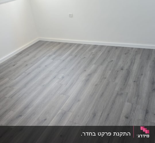 חדר עם רצפת פרקט חדשה ומטאטא בפינה